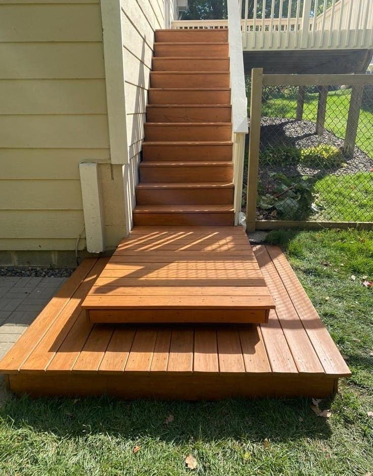 Deck stairs and a landing after cleaning and staining, the wood finished in a warm cedar tone.