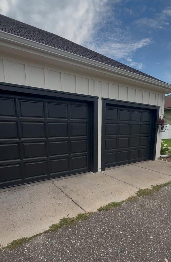 After: the same garage bays finished in black, set against crisp white board-and-batten siding.
