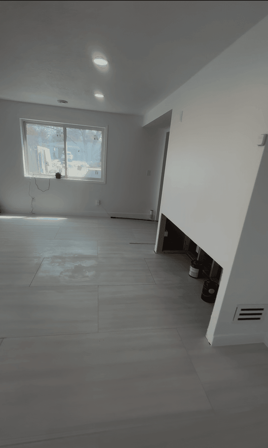 After: the same room painted, with soft gray walls, a white ceiling, and recessed lighting on.